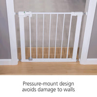 White pressure-mount baby gate on a wooden floor with text indicating it avoids wall damage.